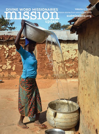 A person pours water from a large metal basin into a pot outdoors in a rural setting. Text on the image includes "Divine Word Missionaries" and "svdmissions.org.